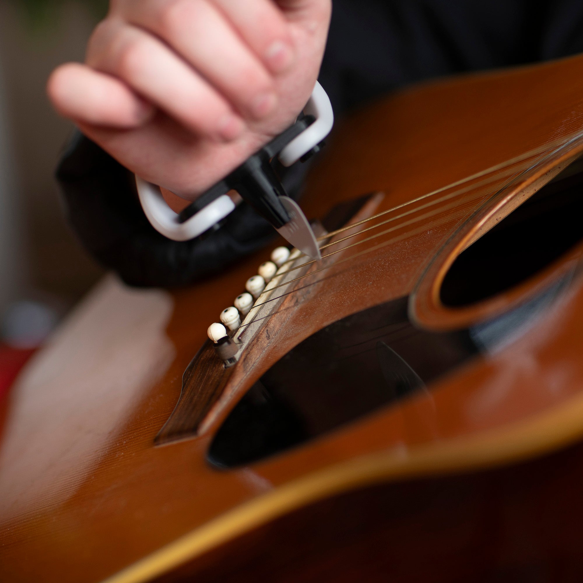 Person strumming an acoustic guitar with a Strumling pick holder on the hand.