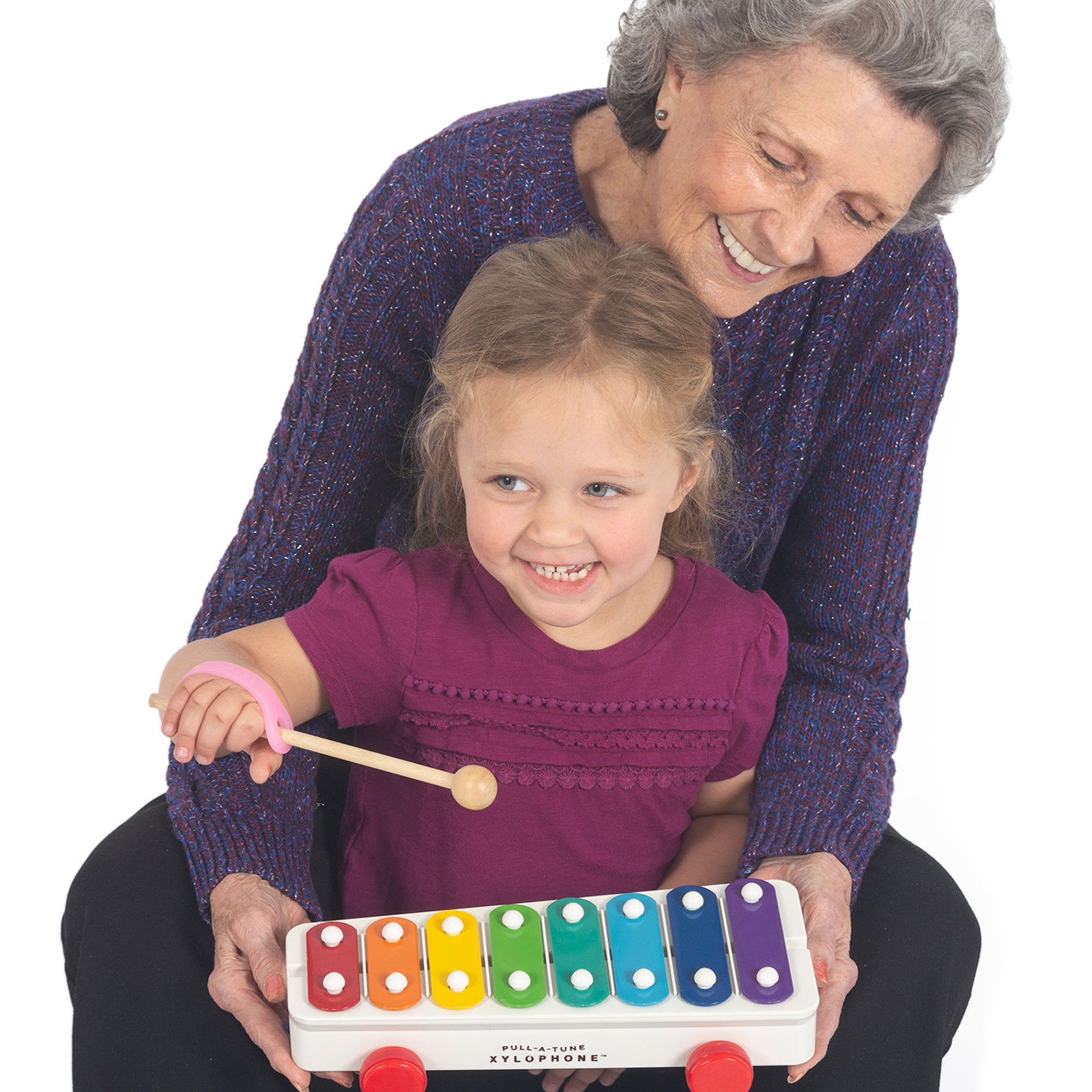 Grandmother and granddaughter playing with a colorful xylophone with a pink EazyHold on the mallet over a white background.