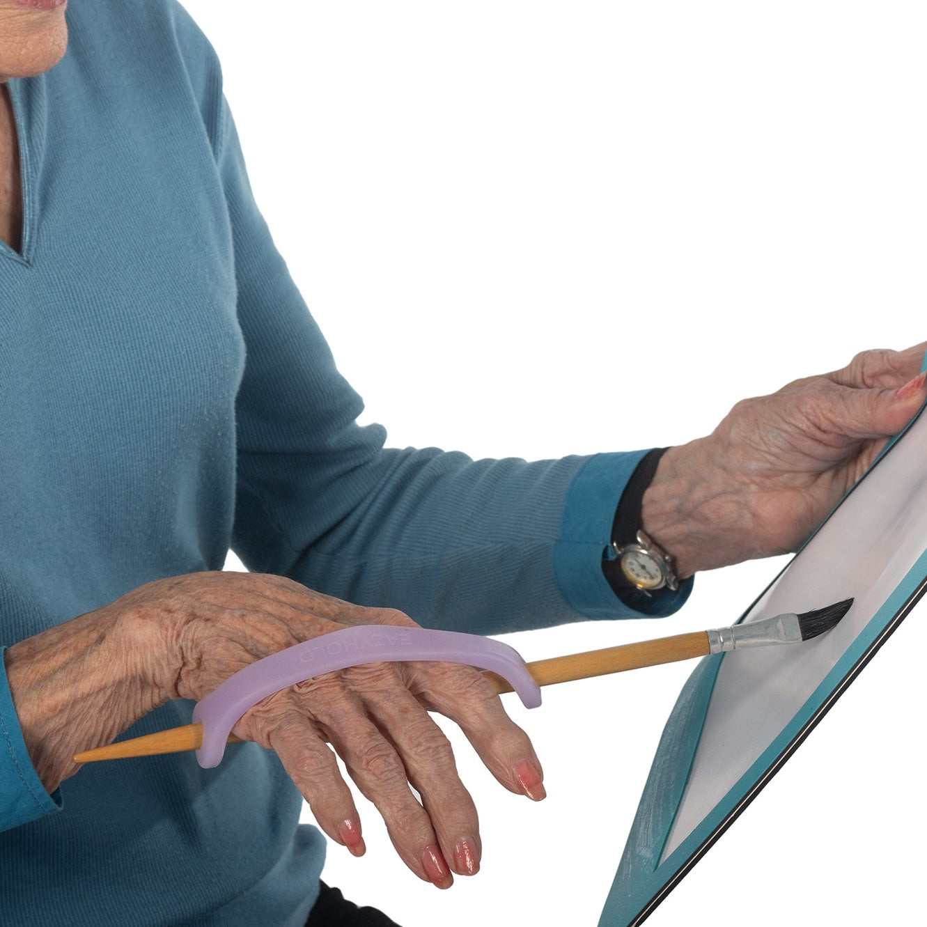 Elderly woman holding a paintbrush with a lavender silicone EasyHold universal cuff.