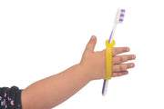 Child with cerebral palsy easily uses a toothbrush with a gripping device made of silicone.