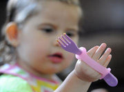 Girl with weak grip holding a fork with help from an eazyhold eating aid.