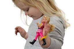 Child with poor motor skills grip holding a doll with a eazy strap on her hand.